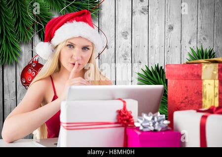 Mujer con el dedo en el labio utilización portátil junto al regalo de navidad Foto de stock