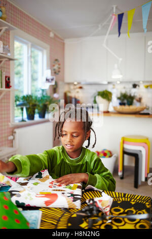 Chica (6-7) jugando con papel decorativo en la cocina Foto de stock