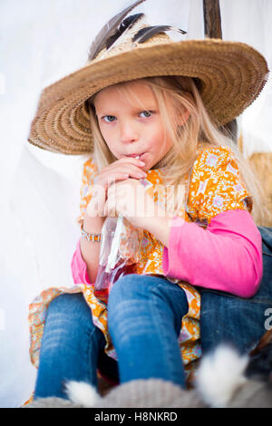 Chica (8-9) llevar sombrero de paja sentados en tienda