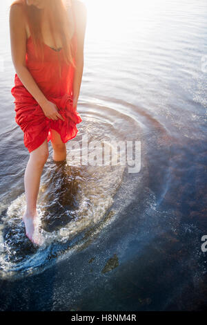 Mujer en el vestido rojo de pie en el lago