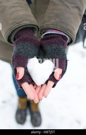 Mujer manos sosteniendo al aire libre de nieve en forma de corazón  Fotografía de stock - Alamy