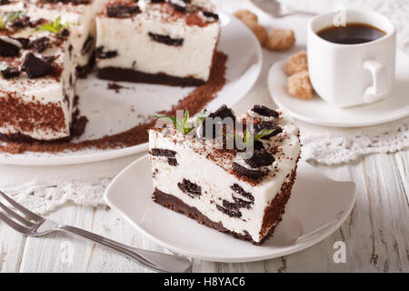 Deliciosa tarta de queso y galletas con trozos de chocolate y café cerca de la mesa horizontal.