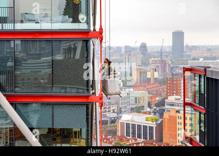 Londres, Reino Unido - 20 de septiembre de 2016 - limpieza de ventanas trabajando en un edificio alto con el paisaje urbano en el fondo Foto de stock
