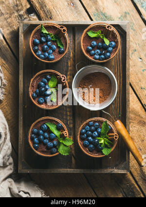 El tiramisú casero con cacao en polvo y el tamiz en bandeja de madera Foto de stock