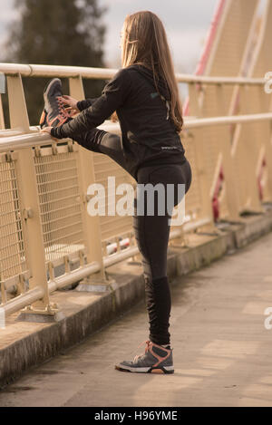 athletic beautiful hot blond stretching on a bridge in black yoga
