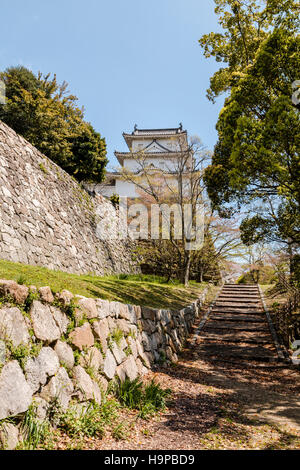 Japón Akashi castillo, AKA Kishun-jo. Tres pisos Hitsujisaru Yagura, torreta, Ishigaki encima de paredes de piedra. Primavera con azul cielo nublado. Foto de stock