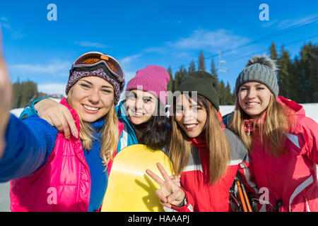 Grupo de gente con el snowboard y el esquí de montaña en invierno la nieve niñas alegres teniendo Selfie Foto Foto de stock