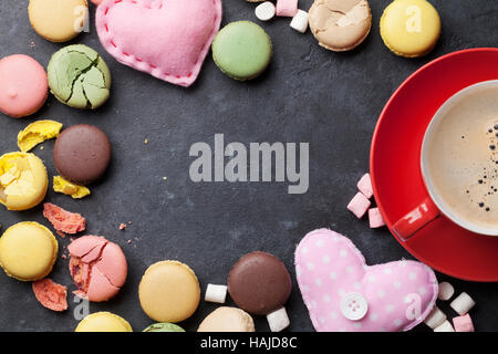 Coloridos macarons y café en la mesa de piedra. Macarons dulces y de los corazones. Vista superior con espacio para copiar el texto