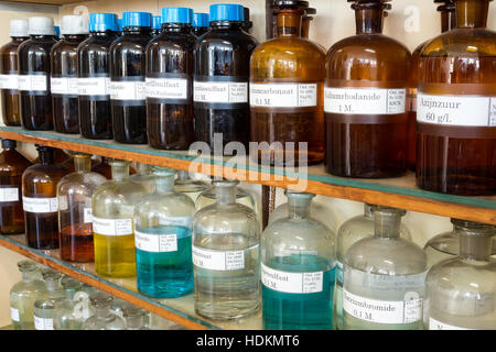Filas de químicos en botellas de vidrio en los estantes en química en la escuela secundaria Foto de stock