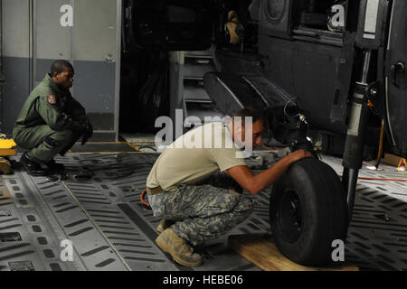 Un ejército de los EE.UU. Jefe de la tripulación, a la derecha, con el 3er Batallón del 160º Regimiento de Aviación de operaciones especiales (SOAR) y una fuerza aérea loadmaster con el 15º Escuadrón Aéreo prepárate para descargar un helicóptero MH-60 Black Hawk desde un avión C-17 Globemaster III en la Base Común de Charleston, Carolina del Sur, el 23 de agosto de 2011. Los aviadores con la 437a grupo de operaciones y soldados con el 160º SOAR realizó una capacitación conjunta para afinar las dos unidades? Habilidades de transporte aéreo. (Ee.Uu. Foto de la fuerza aérea por el Sargento. Nicole Mickle/liberado) Foto de stock