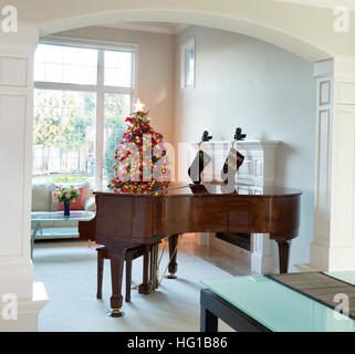 Entrada salón con piano, árbol de Navidad decorado y una gran ventana de luz diurna en segundo plano.