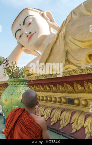 Orando monje en el gigantesco Buda reclinado Myatharlyaung imagen en Bago, Myanmar, Asia Foto de stock