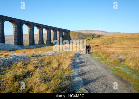 Caminantes pasar el viaducto Ribblehead en su camino a Whernside, Parque Nacional de North Yorkshire, Inglaterra, Reino Unido.