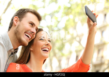 Feliz pareja ocasional teniendo selfie o fotografiar con un teléfono inteligente en la calle