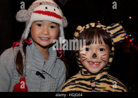 Dos ojos brillantes asiático-americanos jóvenes muchachas en una tapa del mono y el tigre disfraz de Halloween trick or treat. St Paul MN Minnesota EE.UU. Foto de stock