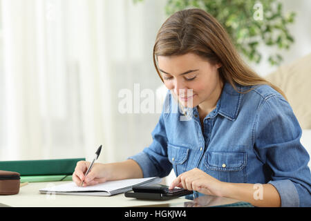 Estudiante de cálculo con una calculadora y escribir notas a mano el emplazamiento en el suelo del salón en casa