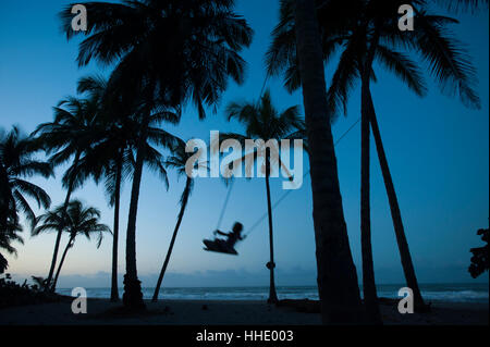Una niña juega en un columpio atado entre palmeras en la costa del Caribe en Palomino en Colombia