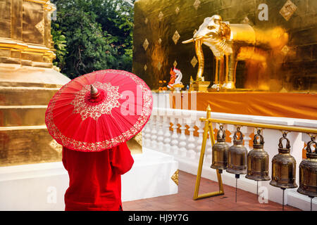 Mujer turista con rojo paraguas tradicional tailandés en Golden templo Wat Phra Singh en Chiang Mai, Tailandia