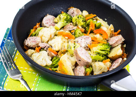 Guiso de verduras con salchichas rebanadas asadas en una sartén a Foto de stock