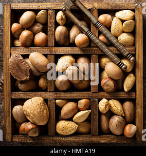 Diferentes nueces con cáscara en una caja de madera Foto de stock
