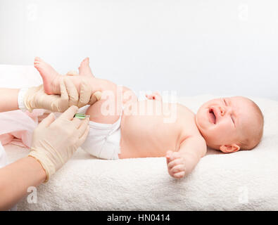 Primer plano de la pediatra dando una niña de tres meses la inyección intramuscular en la pata Foto de stock