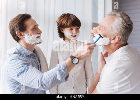 Bonito guapo ayudando a su padre a afeitarse Foto de stock