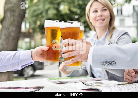Empresarios de tostar los vasos de cerveza en el restaurante al aire libre Foto de stock
