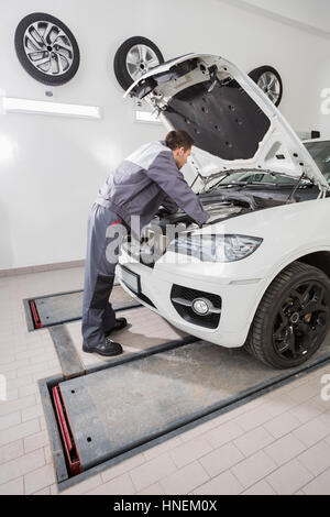 Vista lateral de la longitud completa de machos mecánica de automóviles reparación de motor del coche en el taller de reparación