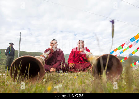 Monjes budistas tibetanos tocan los instrumentos tradicionales para bendecir a los jinetes antes de competición en el Festival de Caballos Manigango alta en la platea tibetano Foto de stock