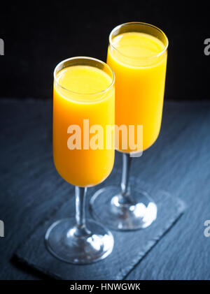 Zumo de naranja recién exprimido en copas de champaña. Foto de stock