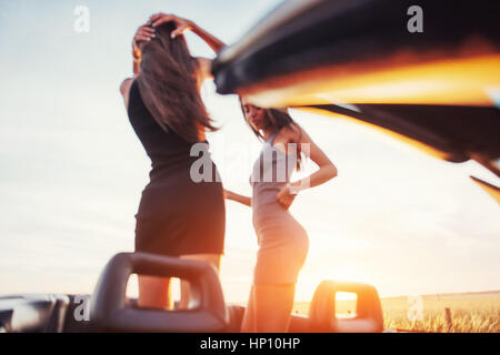 Las niñas encantados de posar junto a un automóvil negro