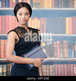 Mujer Africana pararse delante de la estantería con atuendo formal Foto de stock