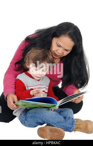 Una niñera filipina sentada con un chico en el suelo y leer el cuento a él, aislados en fondo blanco. Foto de stock