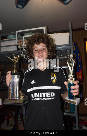 Orgulloso joven jugador de fútbol de 12 años de edad la celebración de dos grandes trofeos ganados por sus esfuerzos atléticos. Downers Grove, Illinois IL USA