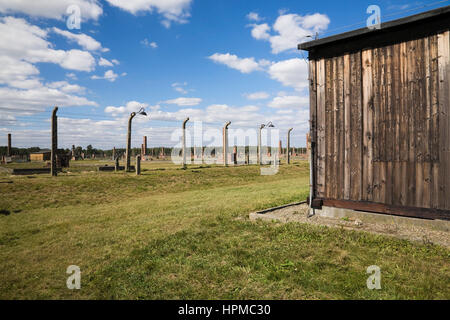 Edificio de dormitorio y alambre de púas cerca electrificada en Auschwitz II-Birkenau ex campo de concentración nazi de Auschwitz-Birkenau, en Polonia, Europa oriental Foto de stock
