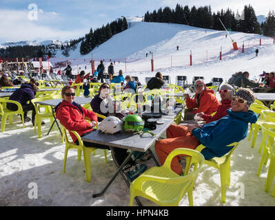 Familiares y amigos de los esquiadores en invierno vacaciones disfrutando del sol restaurantes fuera de un restaurante de esquí en los Alpes franceses. Samoens Ródano-Alpes Francia Europa