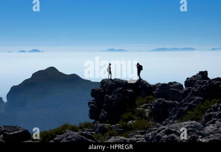 Los turistas tomando fotografías de cada uno de otros en la cima de la montaña de la mesa con la dramática luz temprano por la mañana, Ciudad del Cabo, Sudáfrica