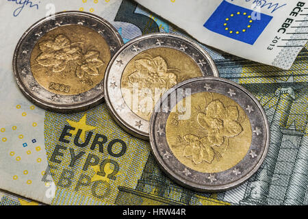 Auf einer 5 Billetes de 2 Euro Muenzen liegen drei von Finnland | Sobre 5 billetes de 2 euros son tres monedas de Finlandia Foto de stock