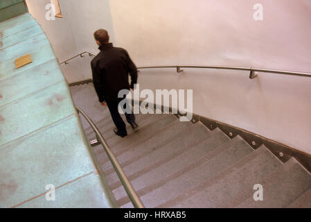 El hombre masculino de alto mirador desde detrás bajando las escaleras Foto de stock