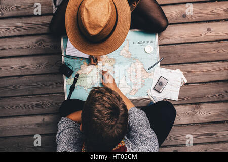 El hombre y la mujer haciendo planes de vacaciones utilizando el mapa del mundo. Pareja sentada por el mapa y explorarlo.