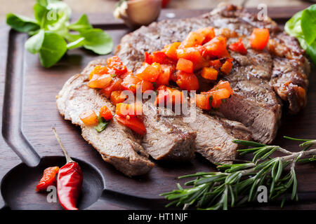 Filete de Carne bien hecha con salsa de tomate y pimienta sobre un fondo de madera.