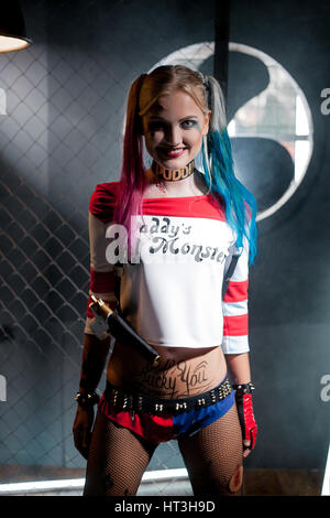 Chica en traje de Harley Quinn. Ella se levanta con un bate y lame el bat.  Cerca. Cosplay Fotografía de stock - Alamy