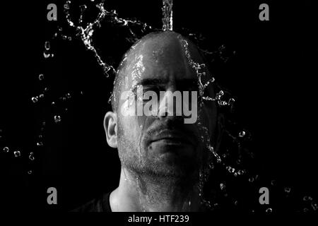 Retrato de un hombre echado agua en la cara contra un fondo negro Foto de stock