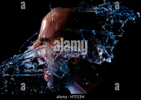 Retrato de un hombre echado agua en la cara contra un fondo negro Foto de stock
