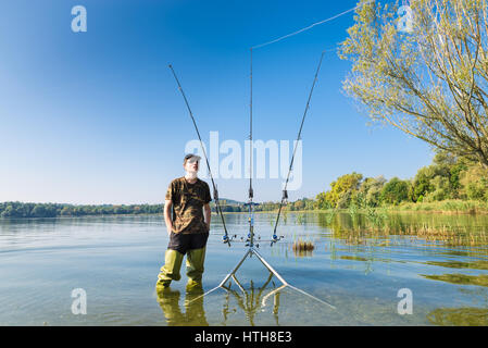 Aventuras de pesca, la pesca de la carpa. Pescador y carpfishing marchas. Pescador con waders verde en el lago