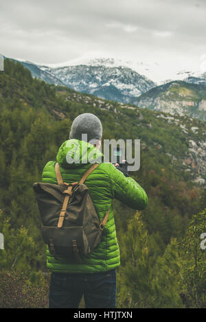 Joven viajero vistiendo ropa brillante hacer fotografía de paisaje