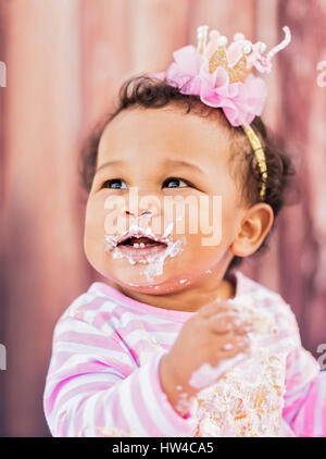 Desordenado raza mixta bebé comiendo pastel de cumpleaños Foto de stock