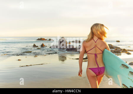 Mujer caucásica llevar tablas de surf en la playa Foto de stock