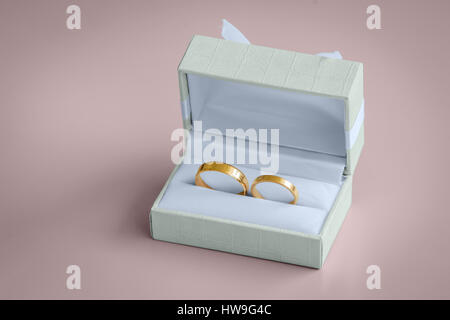 Hermosos anillos de boda de oro dentro de un cuadro de vintage, con arco y decoración de tela Foto de stock