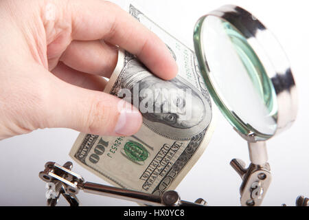 Inspector de Hacienda. Verifica la autenticidad del dinero a través de una lupa. Las manos cerca. Foto de stock